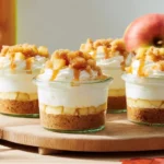 A collection of individual clear dessert cups showcasing layers of diced apples, creamy caramel, and a crumble topping, presented as Caramel Apple Dessert Cups.