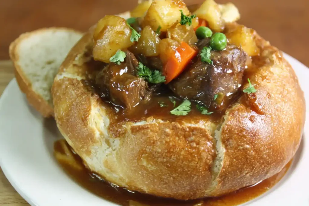 A close-up view of a hearty Beef Stew Bread Bowl, filled with chunky vegetables, tender meat, and garnished with fresh parsley.