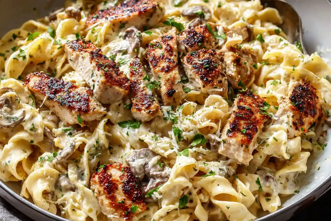 A close-up shot of a serving of Creamy Chicken Pasta, rich with sauce and garnished with fresh herbs.