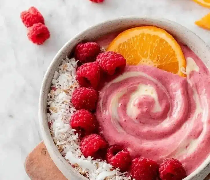 Raspberry Orange Smoothie Bowl topped with fresh fruits and granola